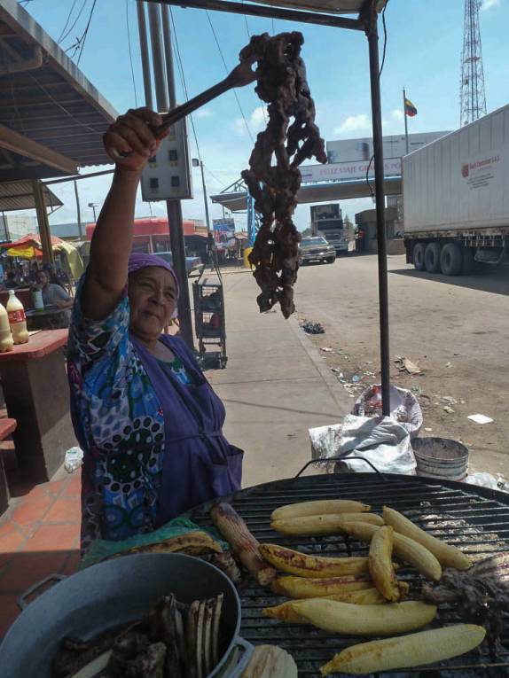 Preparando carne, plátano e queijo na chapa quente, na fronteira da Venezuela